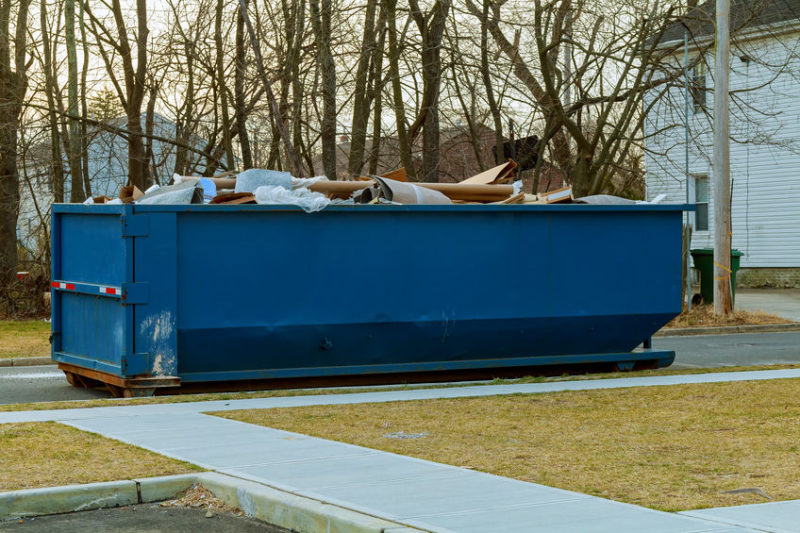 blue dumpster filled with junk